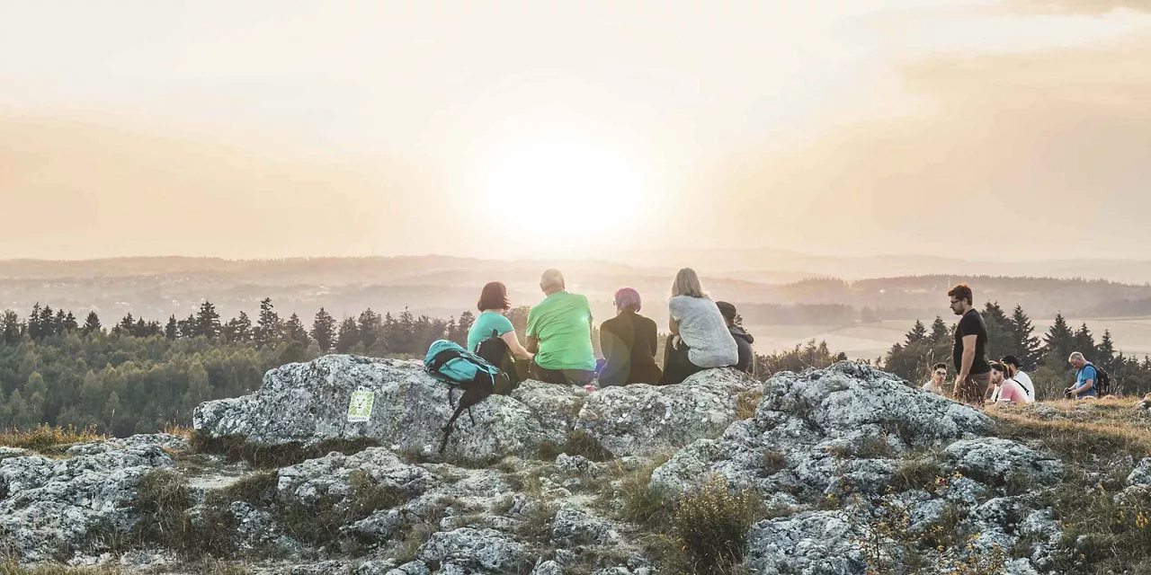 personen-sitzen-auf-steinen-und-genießen-sonnenuntergang-auf-dem-berg