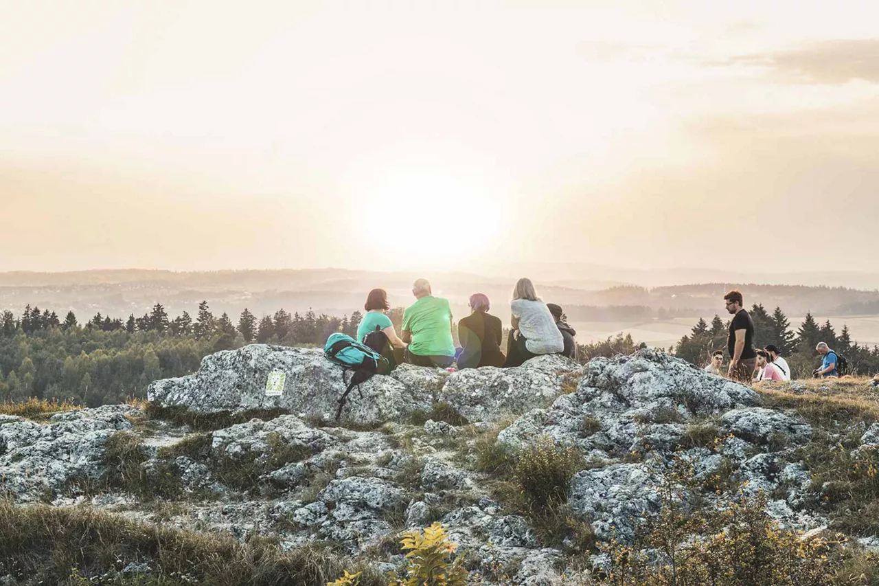 personen-sitzen-auf-steinen-und-genießen-sonnenuntergang-auf-dem-berg