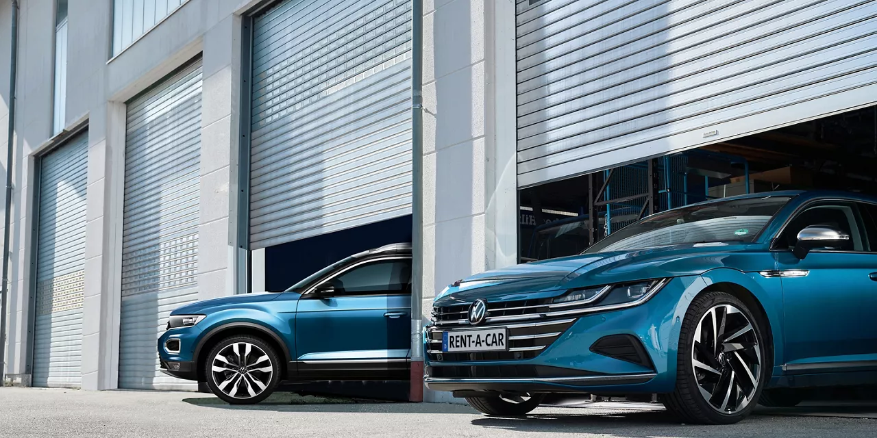 Blauer VW Arteon und blauer VW T-Roc stehen zur Hälfte in einer Lagerhalle