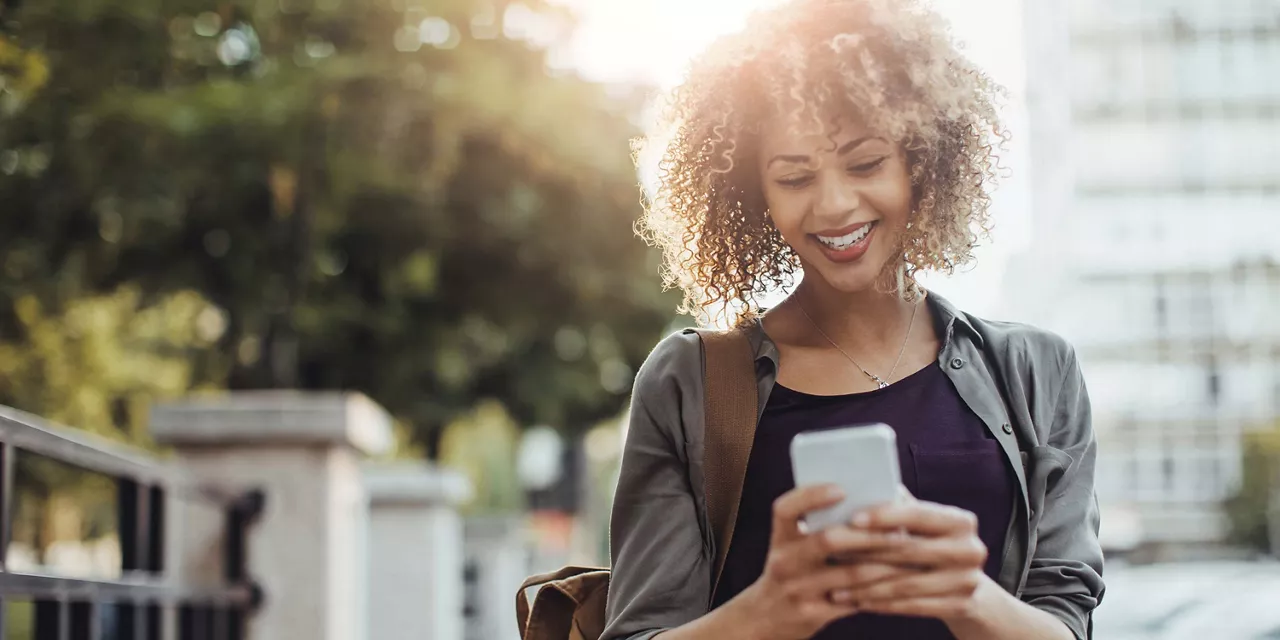 lächelnde-frau-schaut-auf-ihr-smartphone