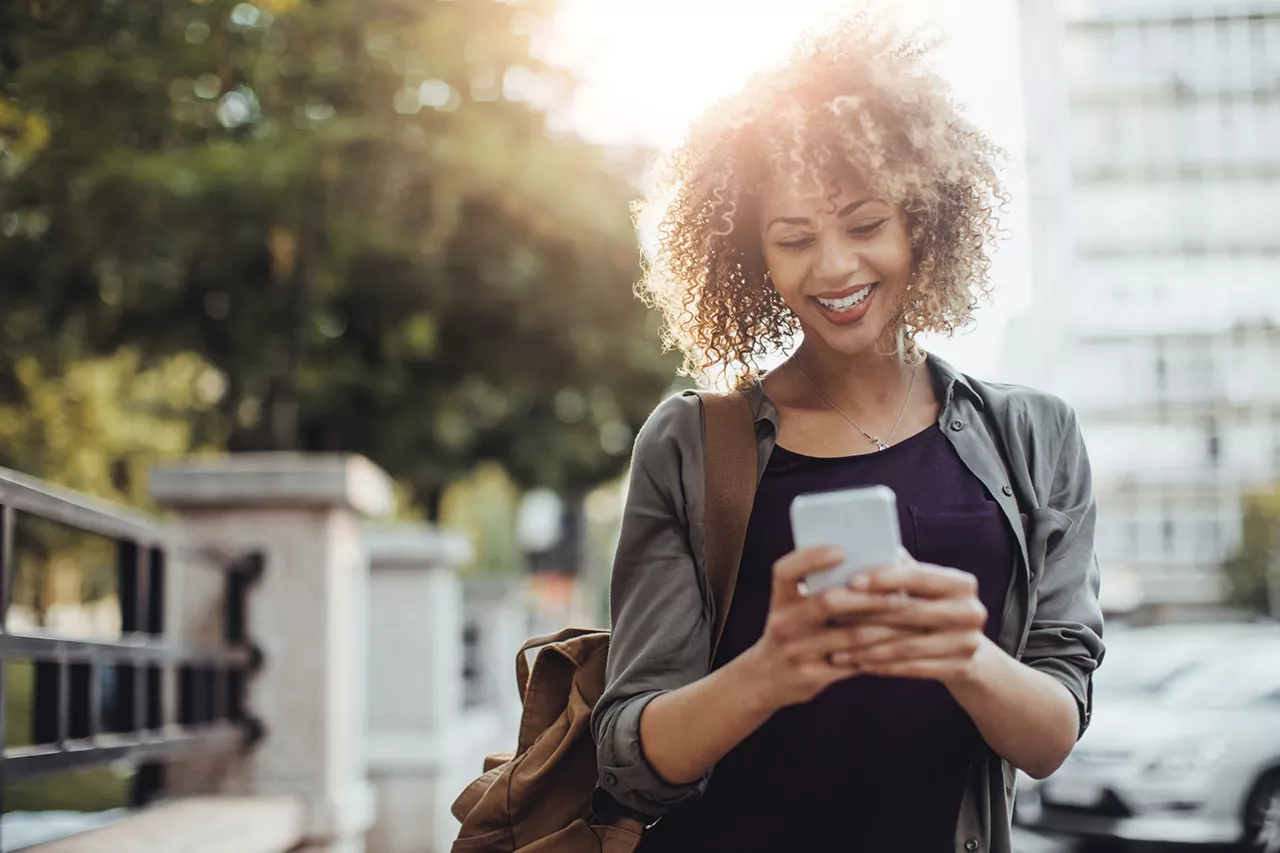 lächelnde-frau-schaut-auf-ihr-smartphone