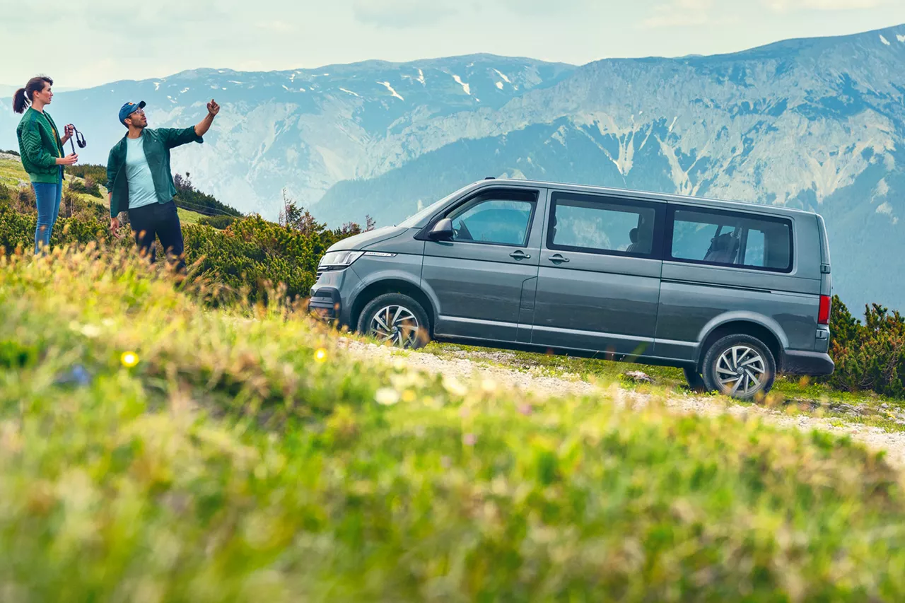 personen-in-den-bergen-machen-fotos-neben-vw-caravelle