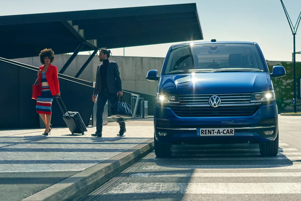 dienstreisende-mit-gepräck-neben-blauer-vw-caravelle 