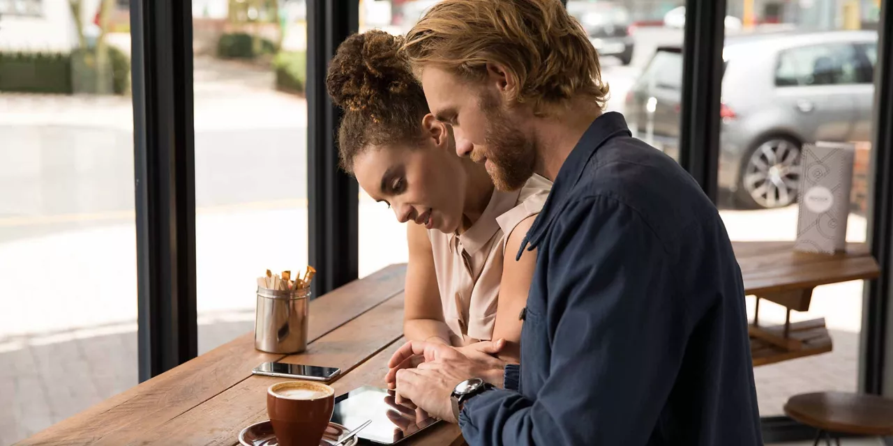 Pärchen in Café nutzt die Online-Services per Tablet.