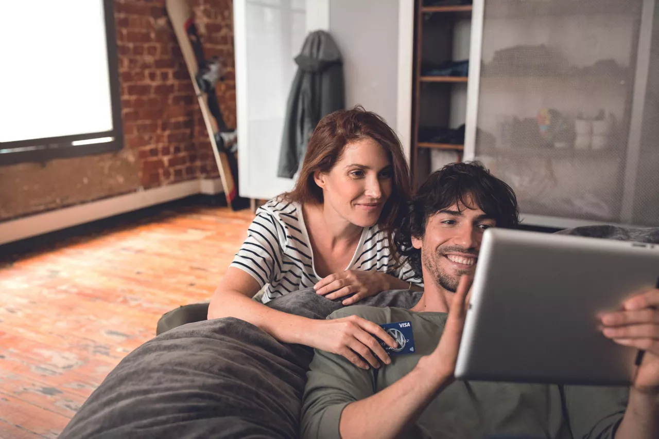 Mann und Frau schauen auf Laptop, wie sie ihren Kredit aufstocken können.