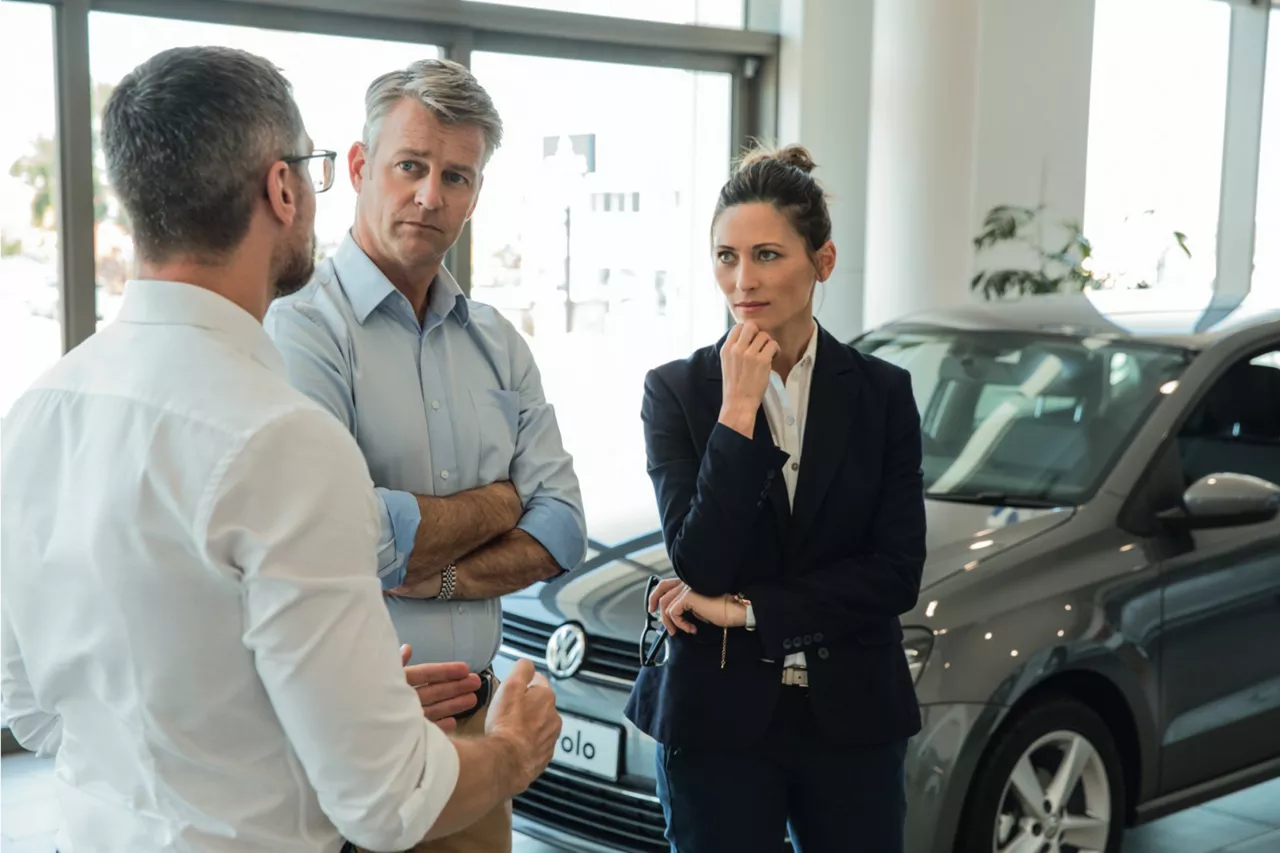 Financiamento Fácil Volkswagen: dois homens e uma mulher em frente a um Polo