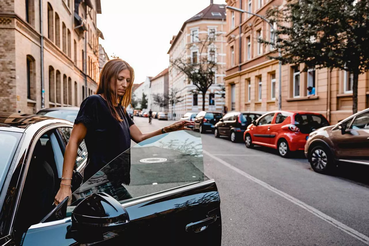 Frau steigt aus einem parkendem Auto am Straßenrand einer Stadt