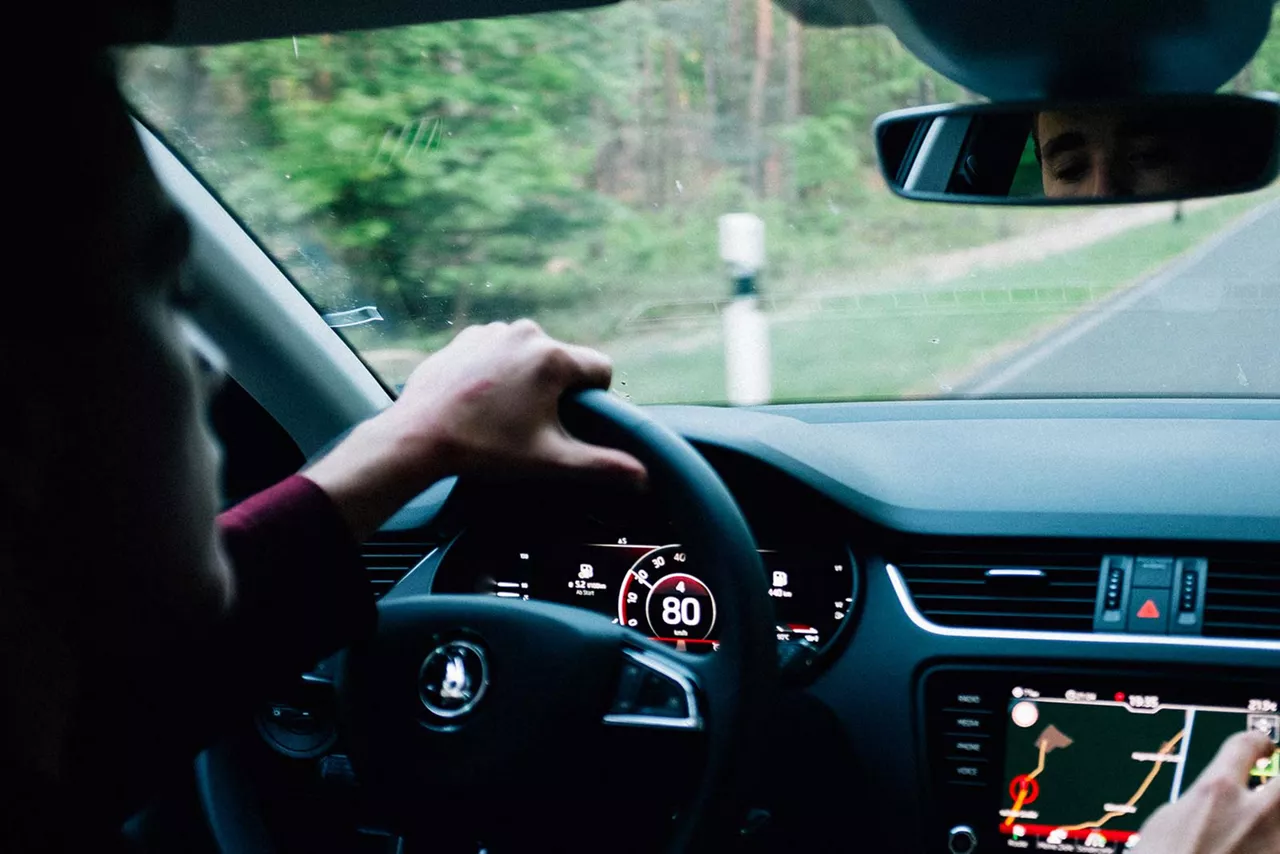 Person sitzt hinter dem Steuer eines Autos mit Blick auf Geschwindigkeitsanzeige