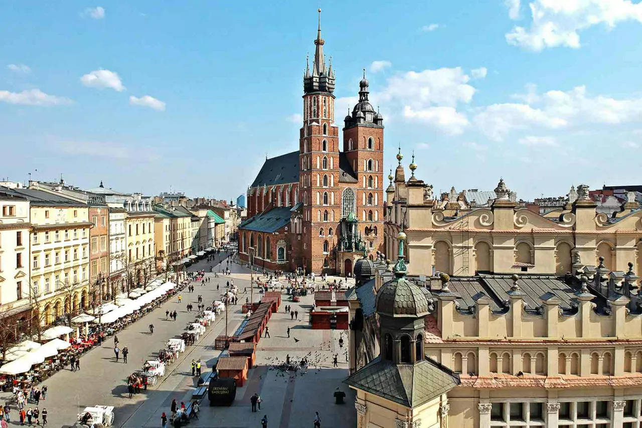 Blick über den Marktplatz von Krakau mit der Marienkirche, historischen Gebäuden und belebtem Platz bei Tageslicht