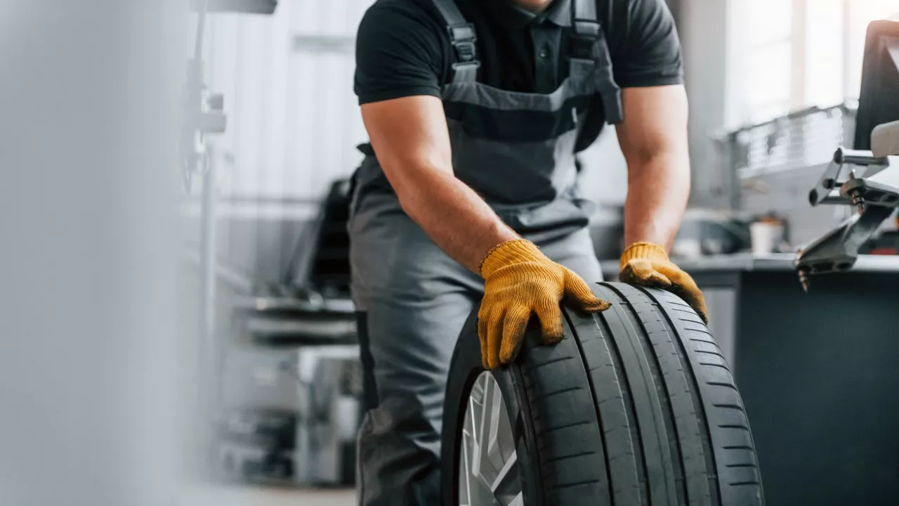 Mechaniker tragen Reifen durch die Werkstatt.