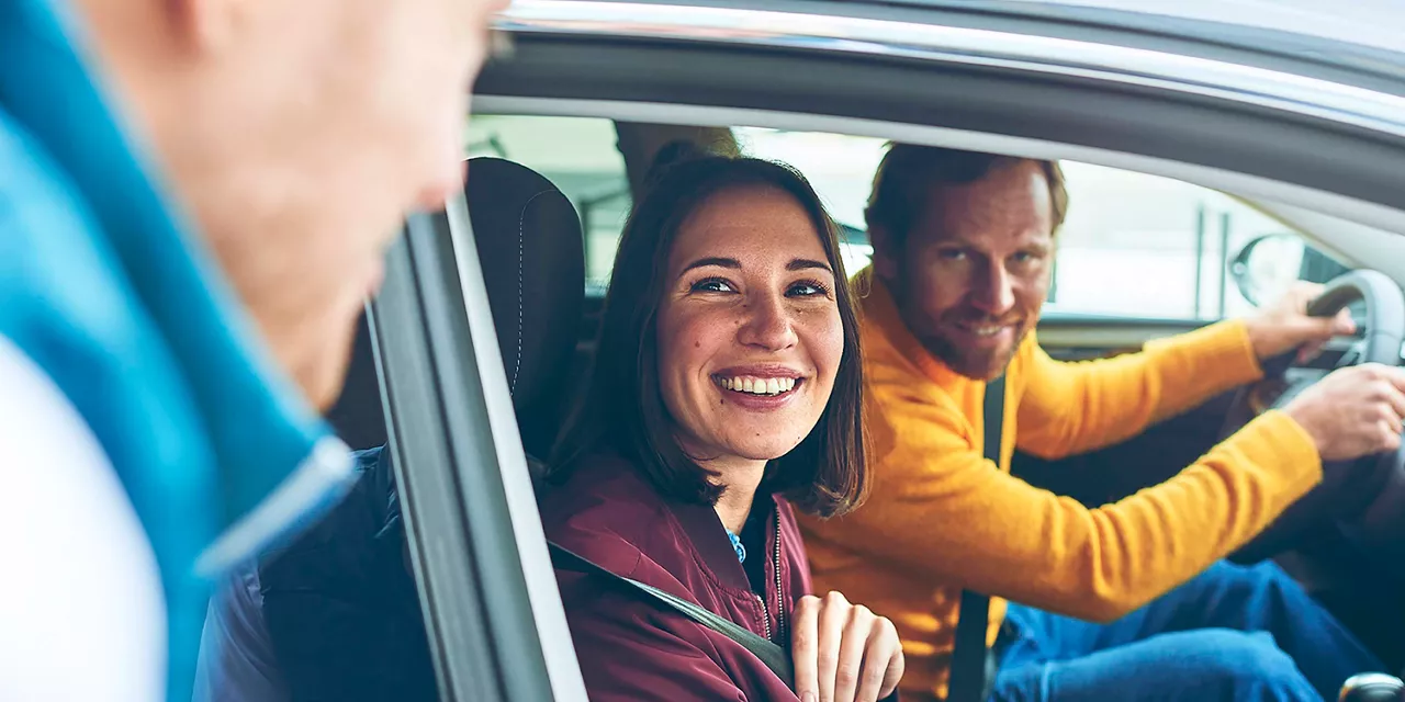 vermietrepräsentant-der-autovermietung-vw-fs-rent-a-car-verabschiedet-im-auto-sitzende-kundschaft