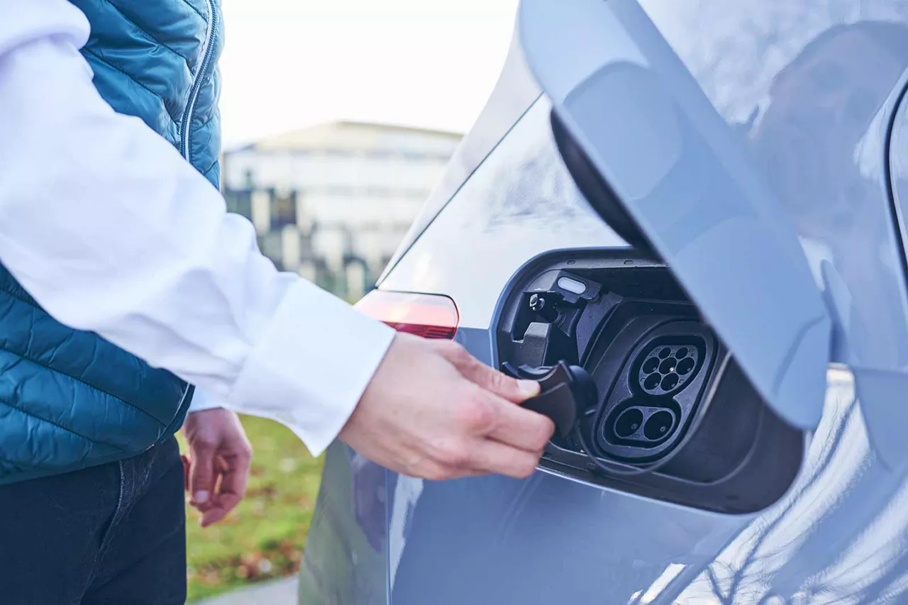 person-schließt-ladebuchse-an-einem-elektroauto-nach-ladevorgang