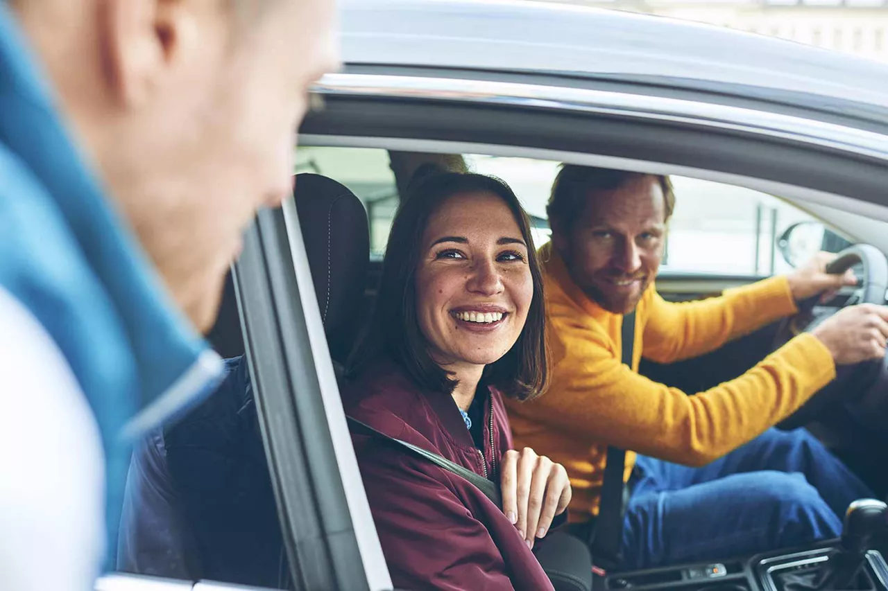 vermietrepräsentant-der-autovermietung-vw-fs-rent-a-car-verabschiedet-im-auto-sitzende-kundschaft