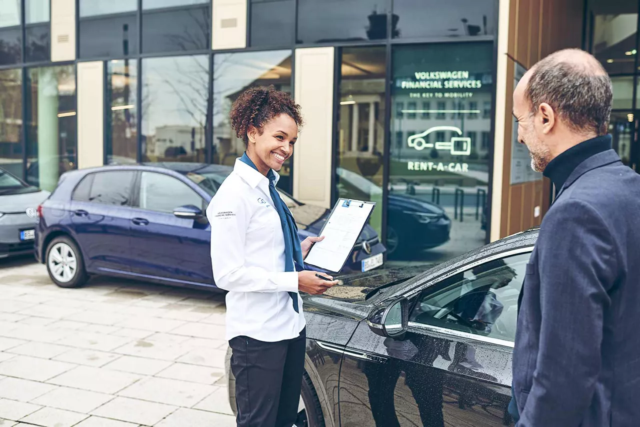 vermietrepräsentantin-der-autovermietung-vw-fs-rent-a-car-sitzt-neben-einem-kunden-auf-dem-beifahrersitz