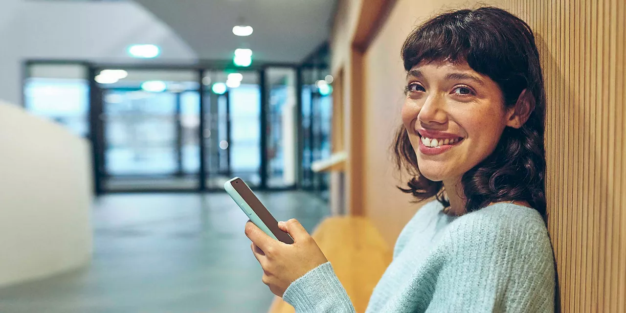 frau-am-smartphone-lächelt-in-die-kamera