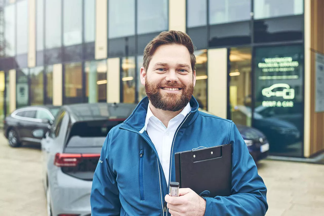 lächelnder-vermietrepräsentant-der-autovermietung-vw-fs-rent-a-car-vor-vermietstation