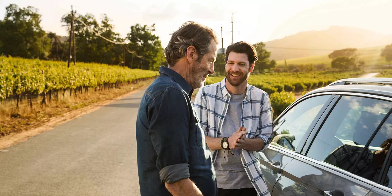 Vater und Sohn neben Auto nutzen Mobilität und Services von VWFS.