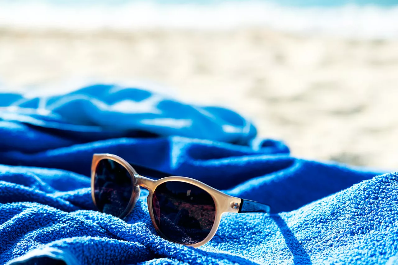 sonnenbrille-auf-blauen-handtuch-am-strand