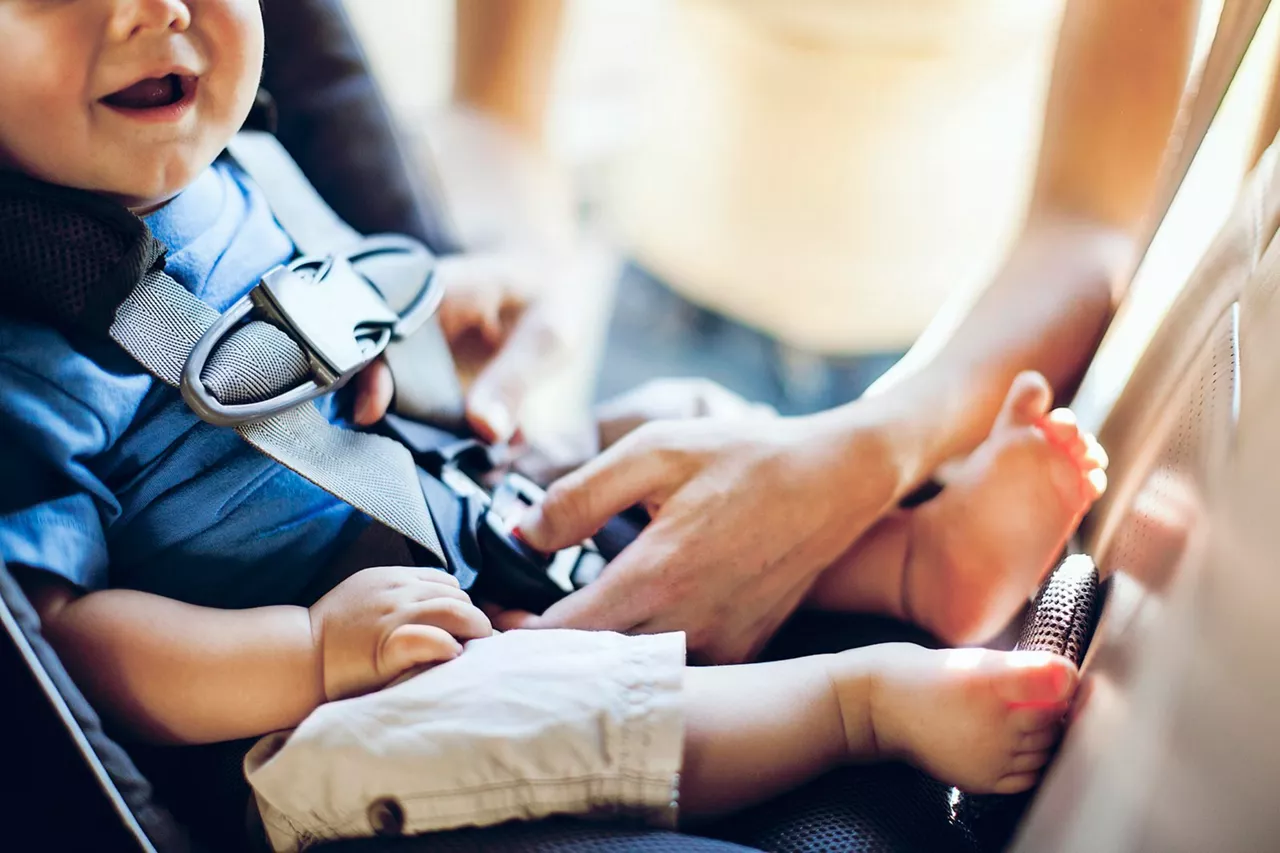 Ein Baby wird sorgfältig im Kindersitz angeschnallt
