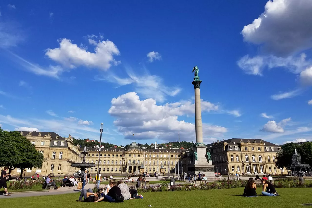 menschen-sitzen-auf-grünfläche-vor-historischen-gebäude