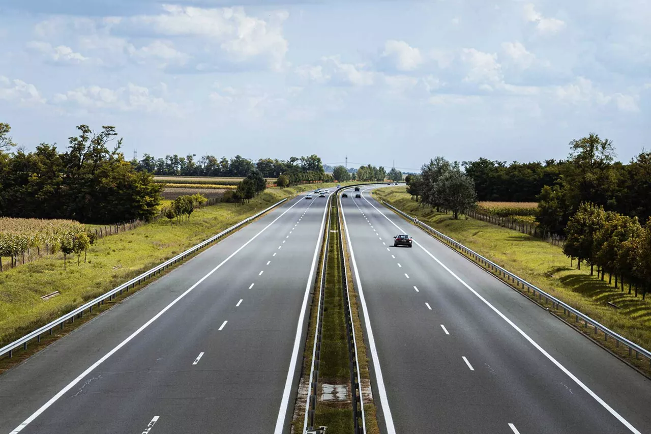 vierspurige-autobahn-mit-fahrzeugen-und-von-natur-umgeben