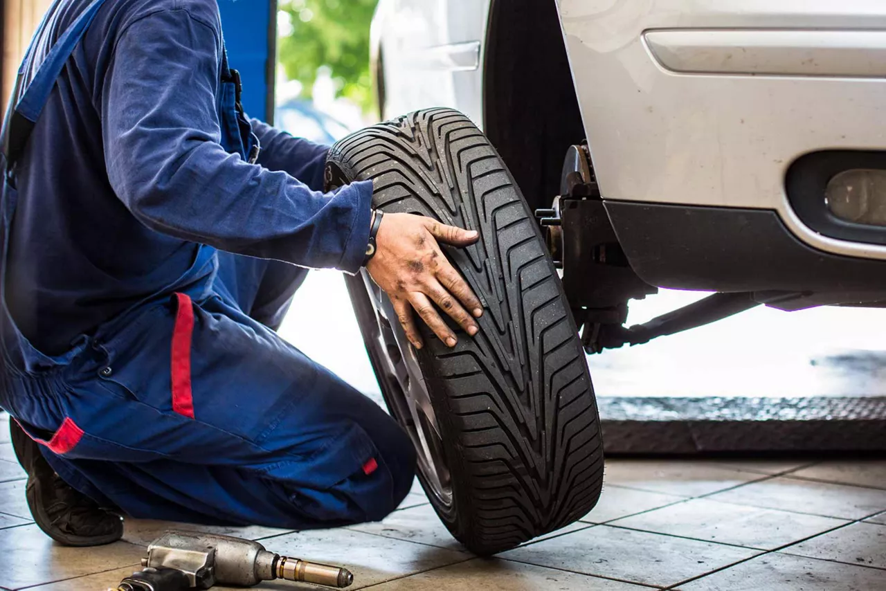 Eine Person wechselt in einer Werkstatt einen Reifen an einem weißen Auto