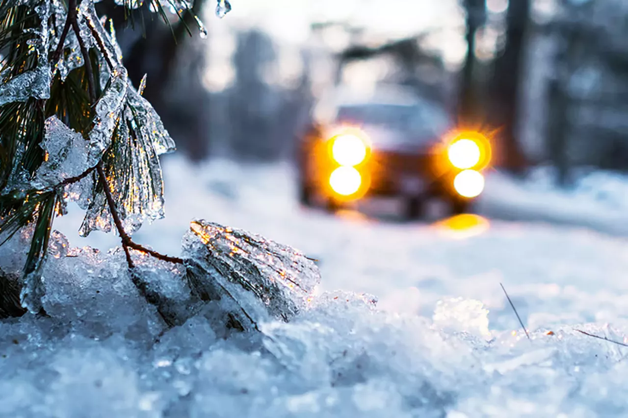 auto-mit-eingeschalteten-scheinwerfern-fährt-durch-schneelandschaft