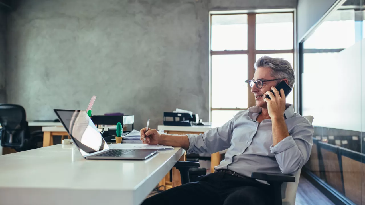 Ein Geschäftsmann sitzt am Schreibtisch in seinem Büro und nutzt das Kapitalkonto Business