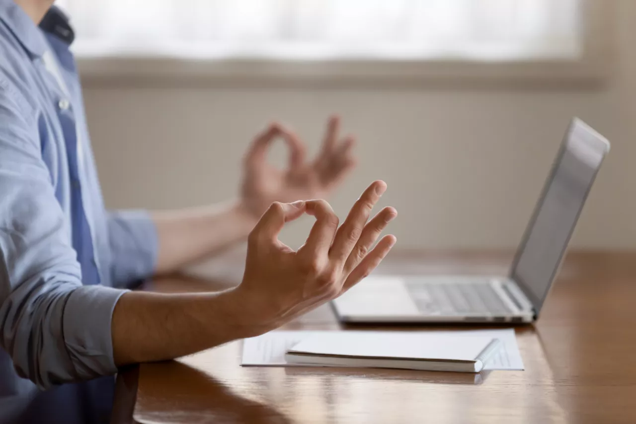 Person meditiert vor dem Laptop