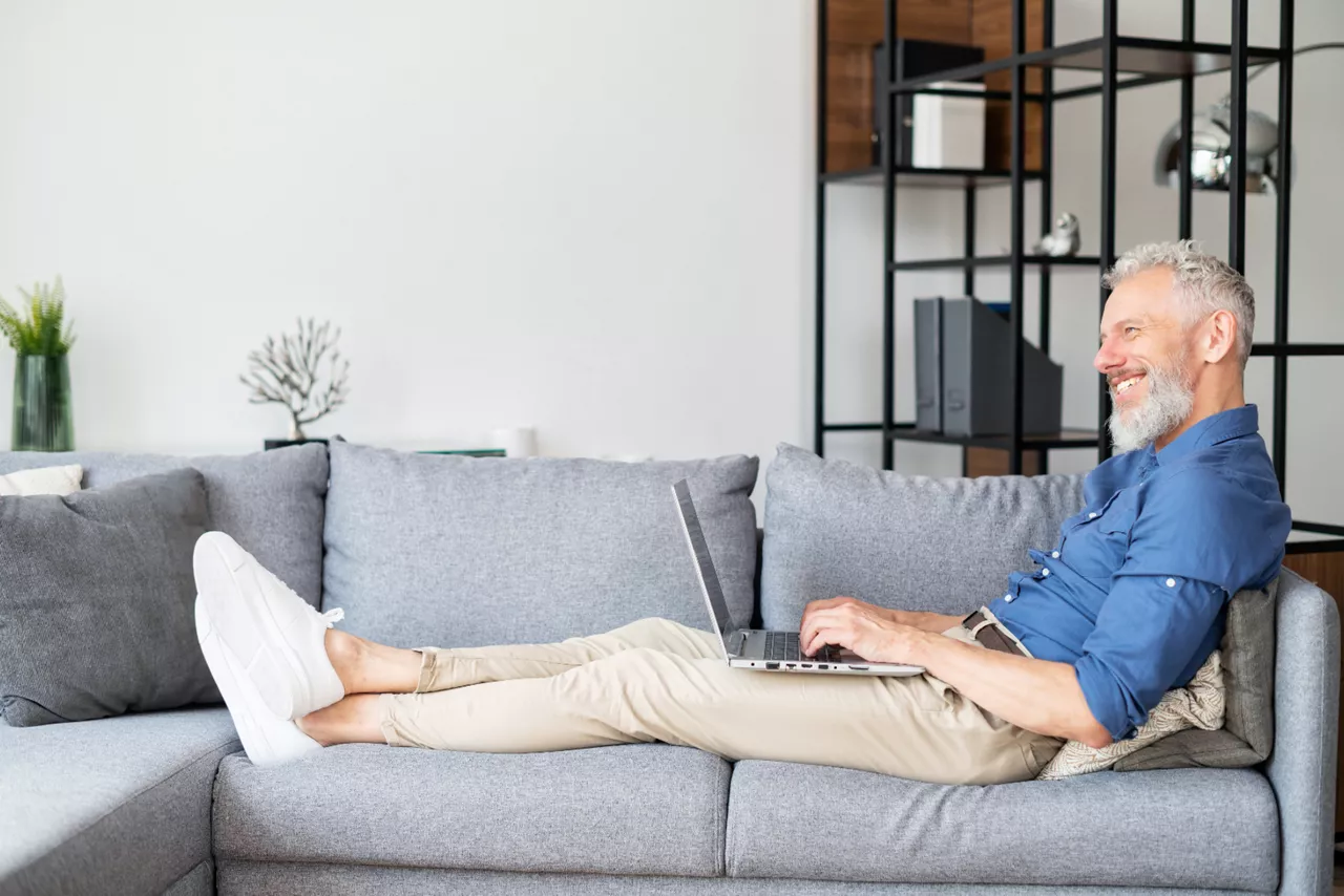 Mann am See mit Laptop, prüft sein Erspartes