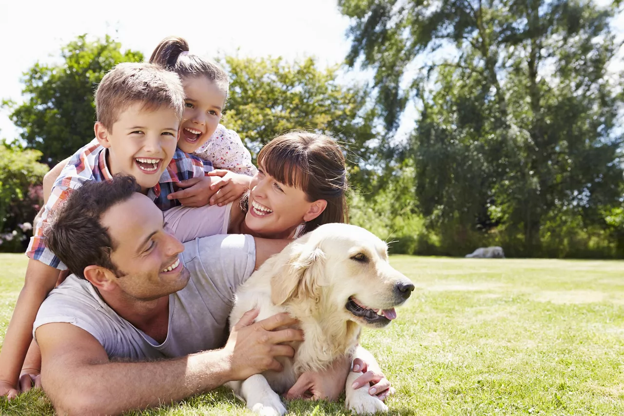 Familie liegt mit Hund im Garten