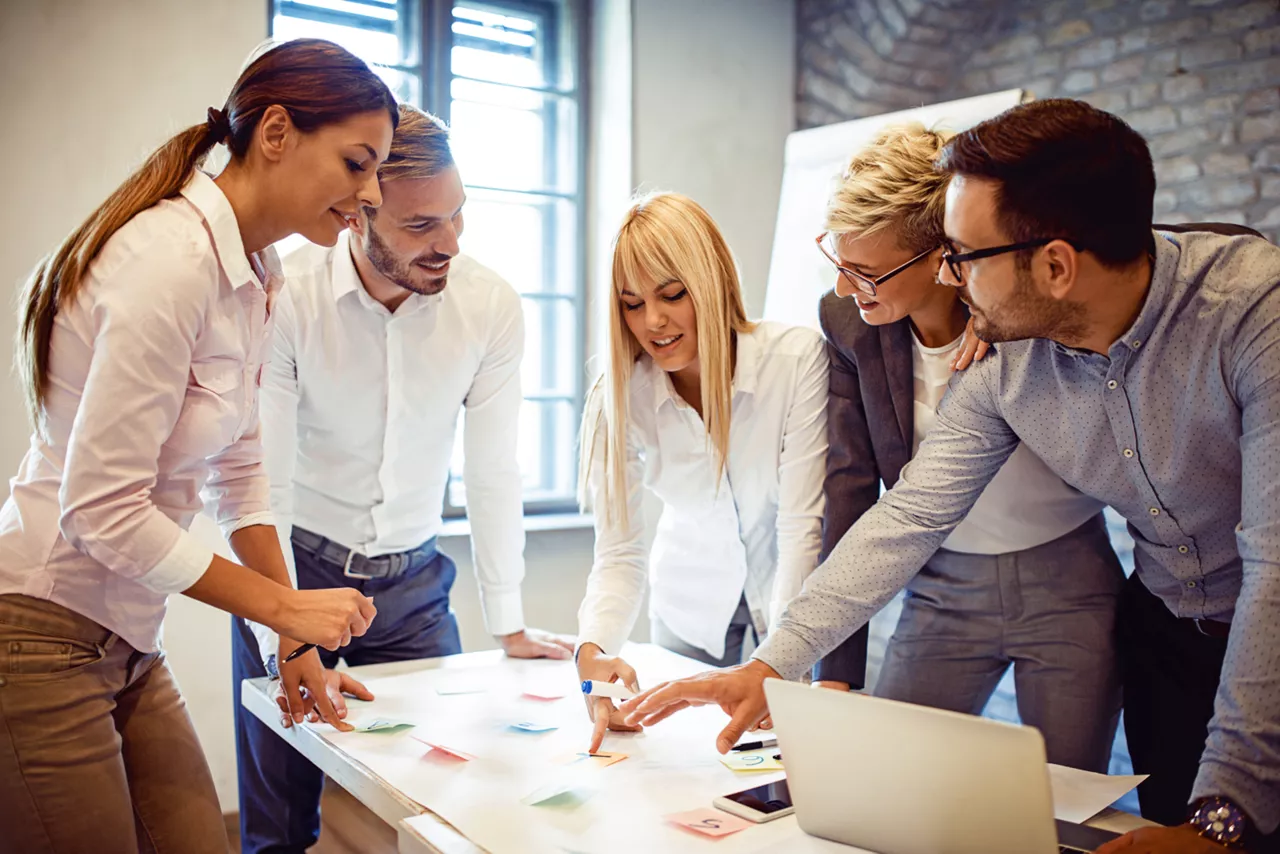 Team steht gemeinsam am Arbeitsplatz