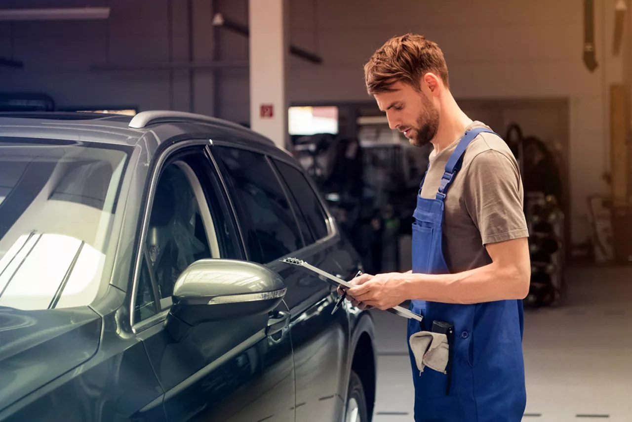 person-in-latzhose-in-einer-werkstatt-schaut-auf-klemmbrett