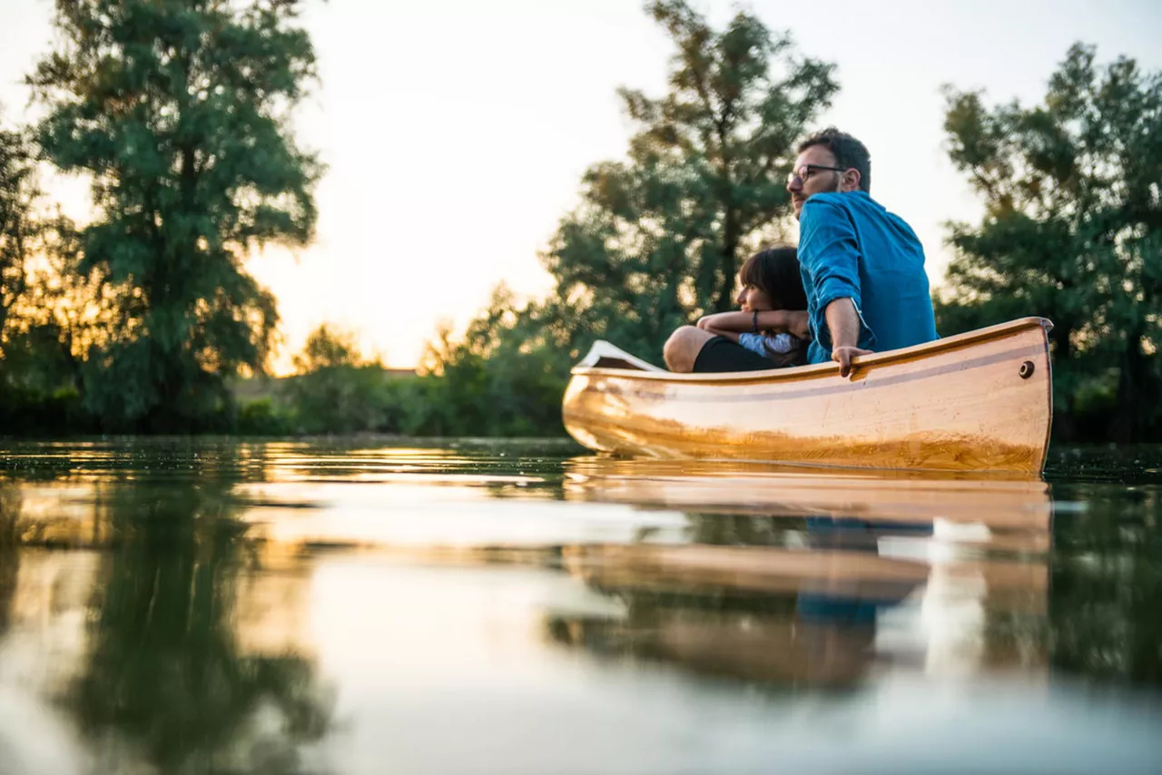 Zwei Personen in einem Kanu gleiten über das Wasser bei Abenddämmerung