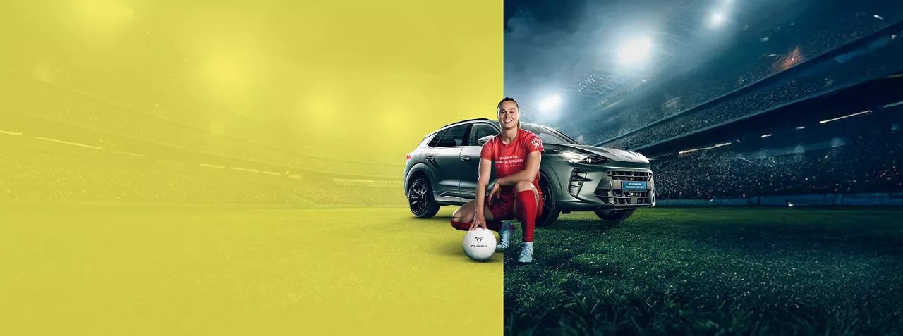 Piłkarka Ewa Pajor przykucnięta z piłką na murawie, za nią samochód Cupra Terramar, w tle stadion wypełniony publicznością.