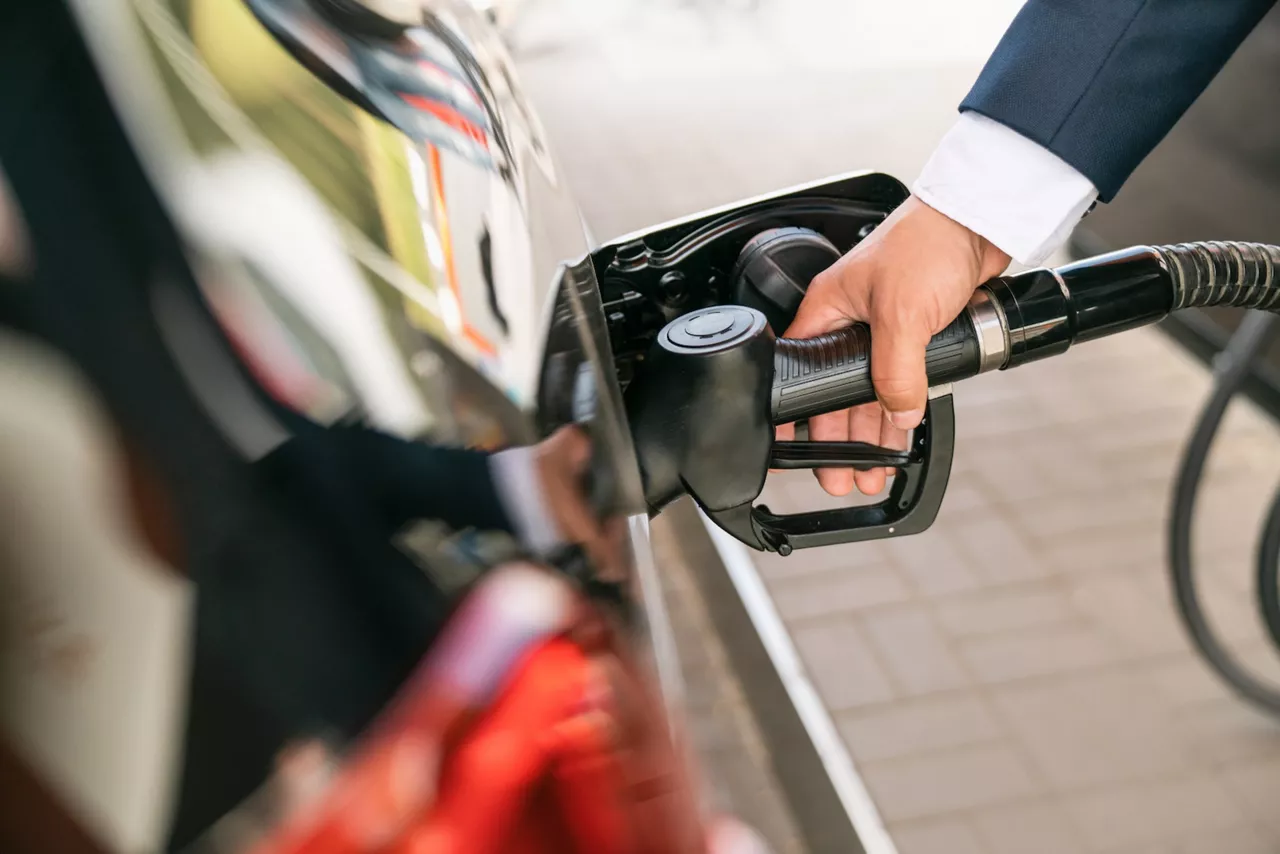 Nahaufnahme eines Manns, der an einer Tankstelle sein Auto betankt.