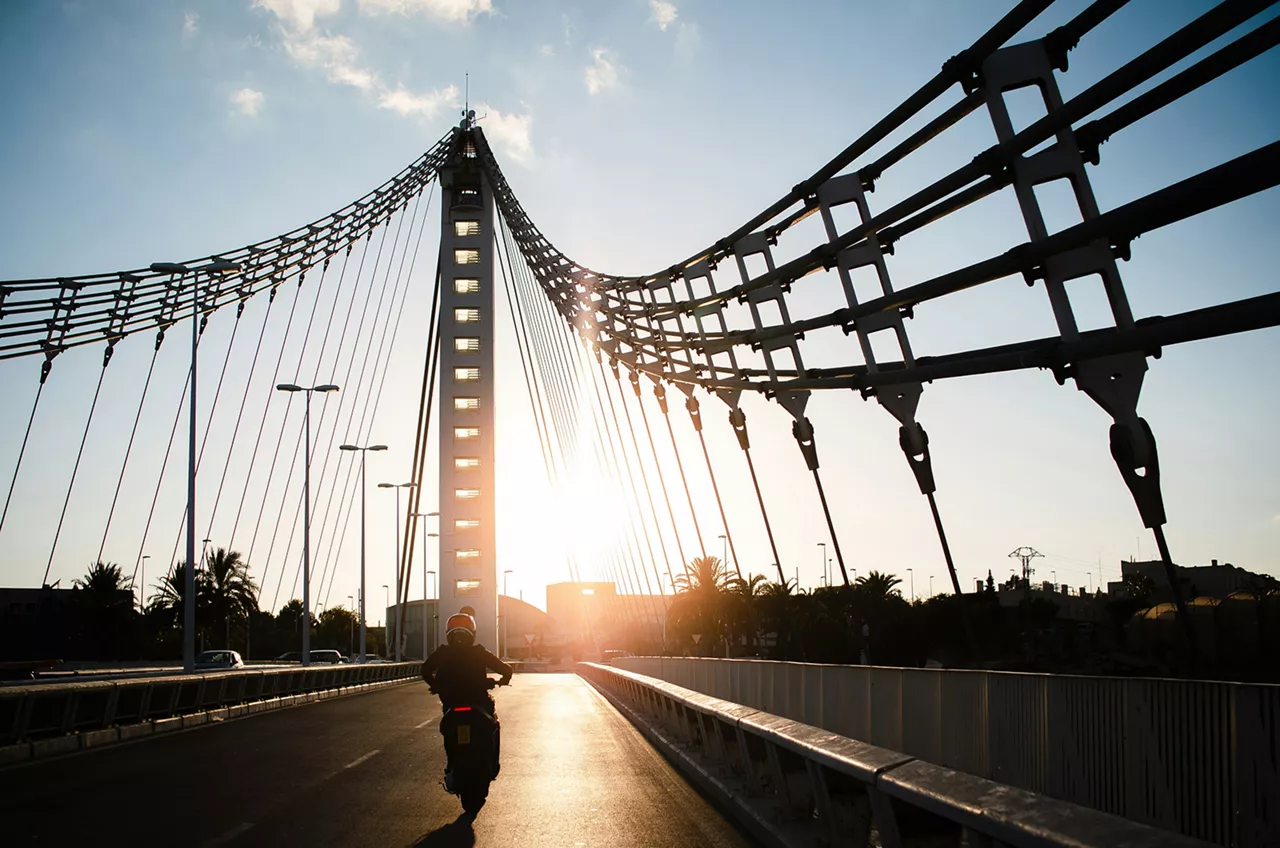 motorrad-fährt-auf-einer-brücke-richtung-sonnenuntergang