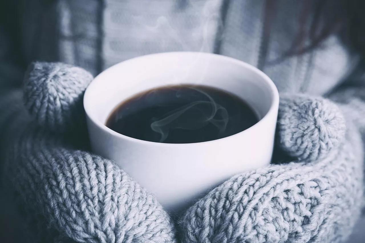 person-hält-kaffeetasse-mit-handschuhen