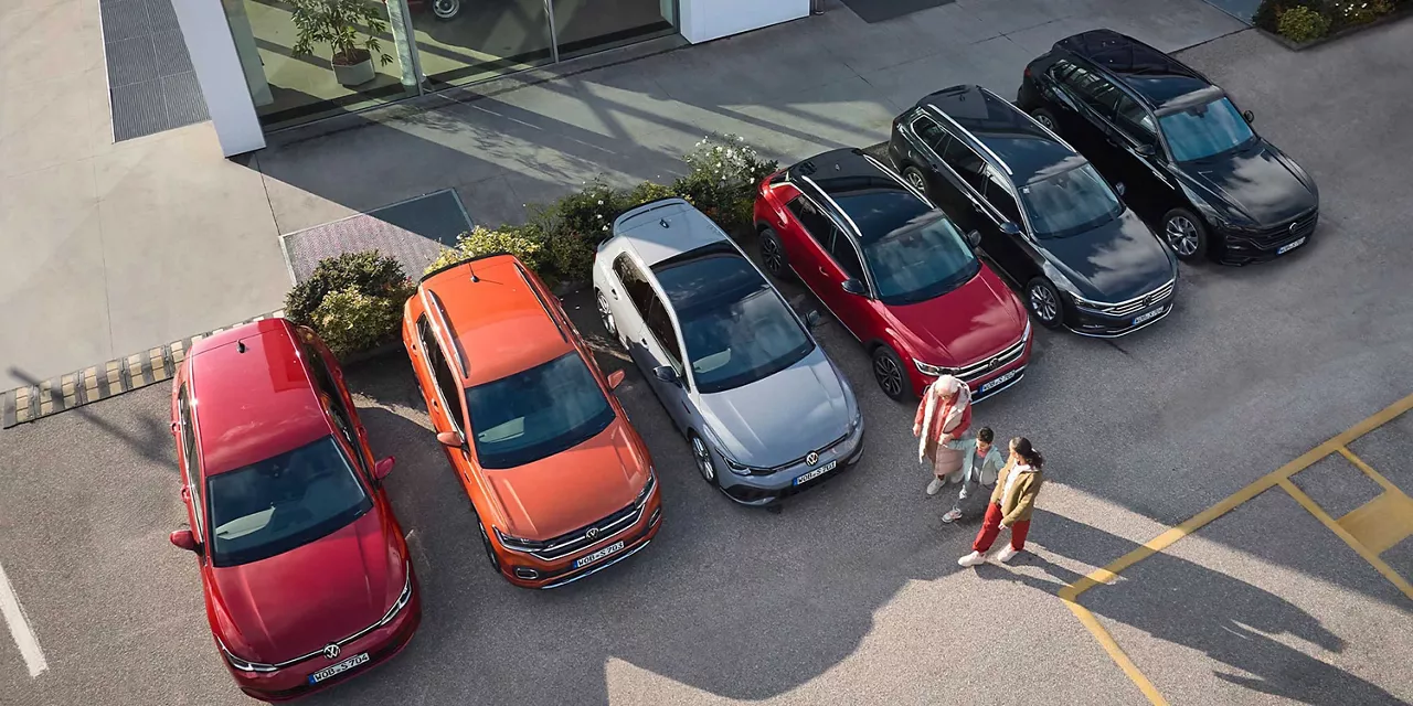 Verschiedene Fahrzeugmodelle von Volkswagen stehen nebeneinander gereiht auf einem Parkplatz