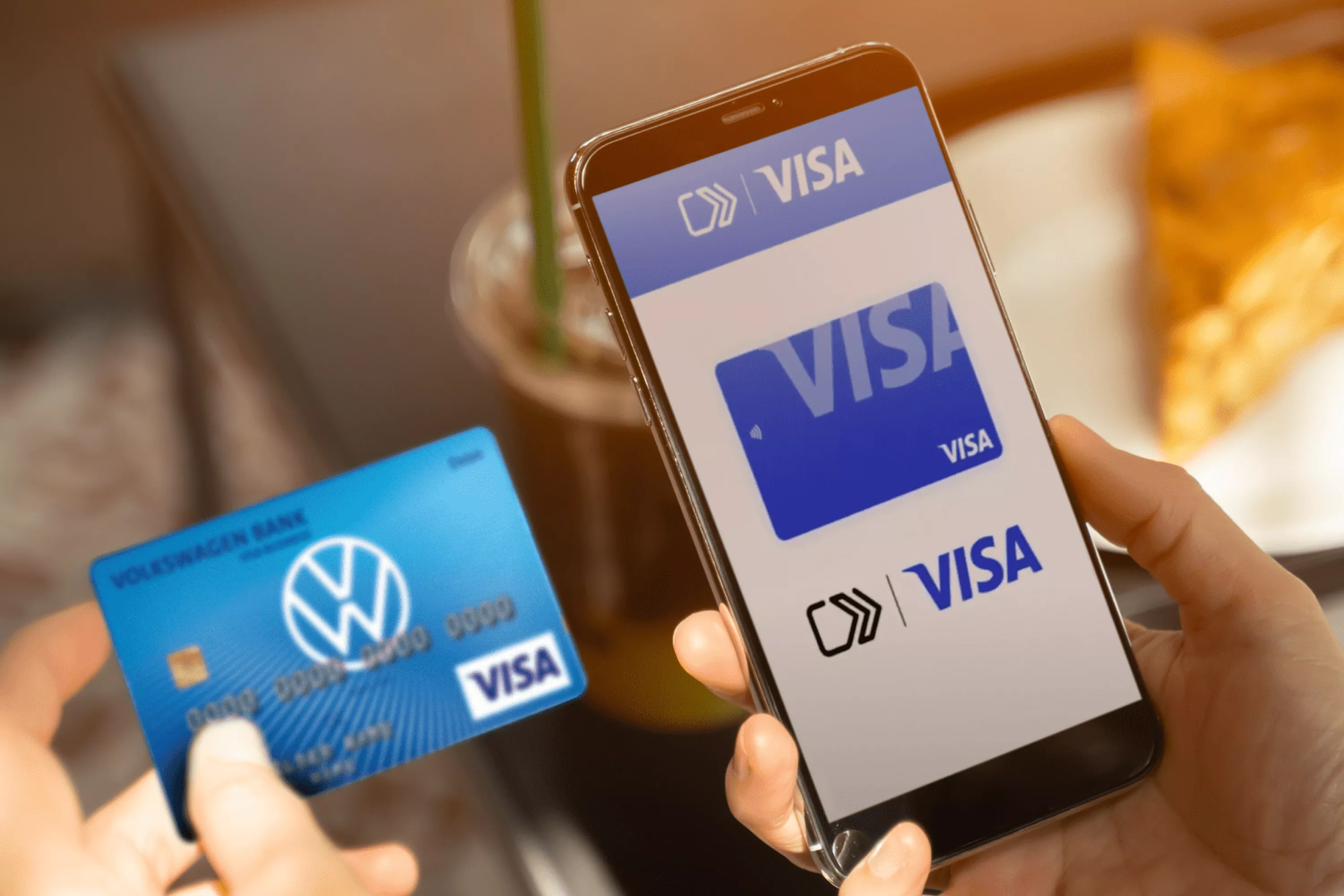Osoba, która trzyma w jednej ręce kartę bankową, a w drugiej telefon komórkowy z wirtualny kartą Visa.