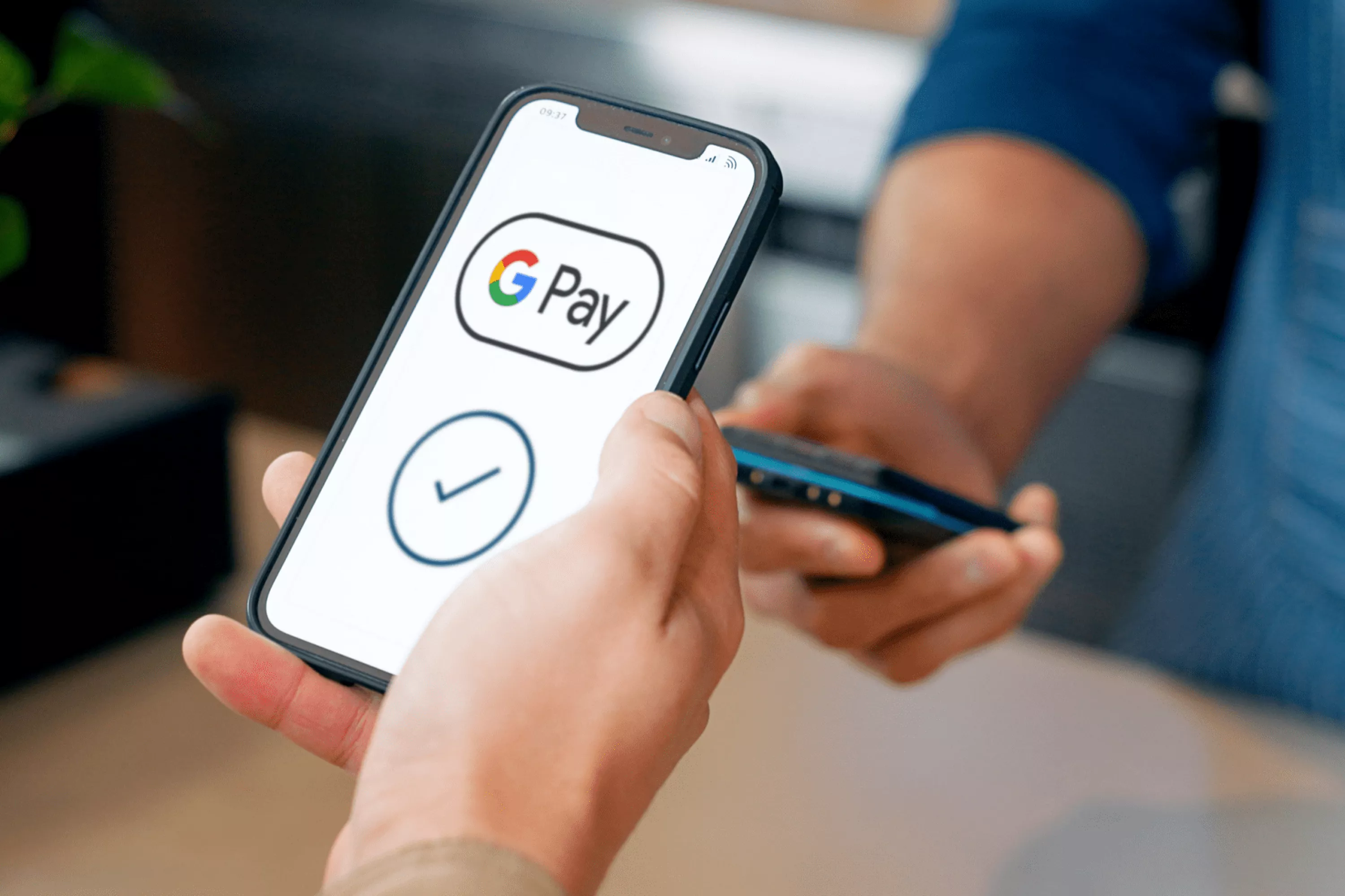 Osoba przykładająca telefon z ikoną Google Pay do terminala.