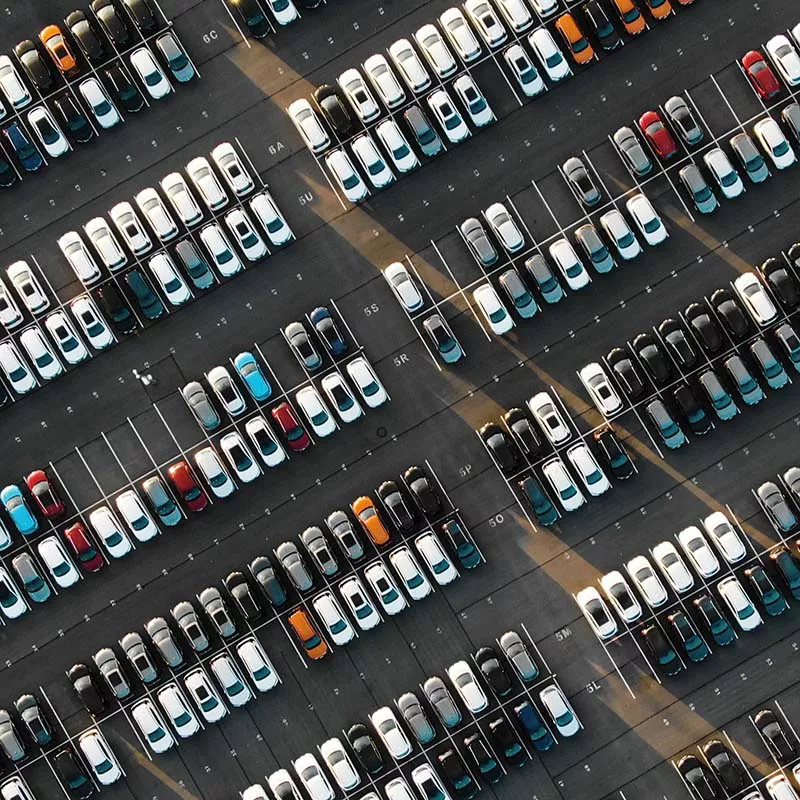 Ogromny parking z rzędami zaparkowanych samochodów.